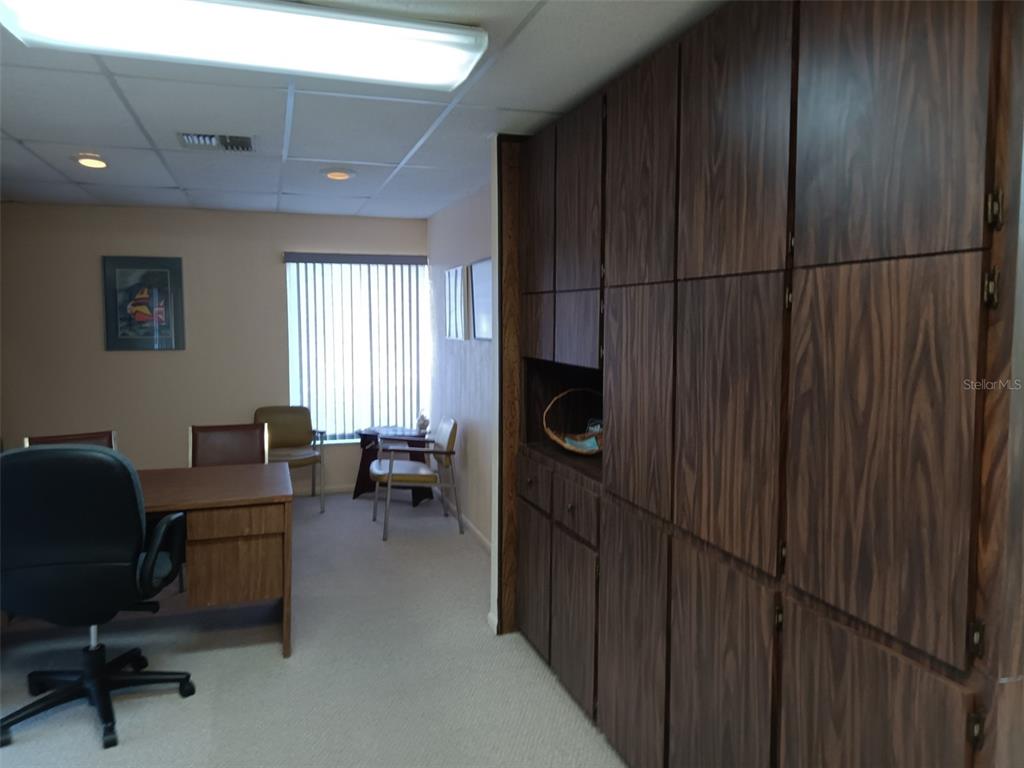An office space features a wooden desk, chairs, and a large wall of wood-grain cabinets — 6967 SUNSET DRIVE S, ST PETERSBURG, FL