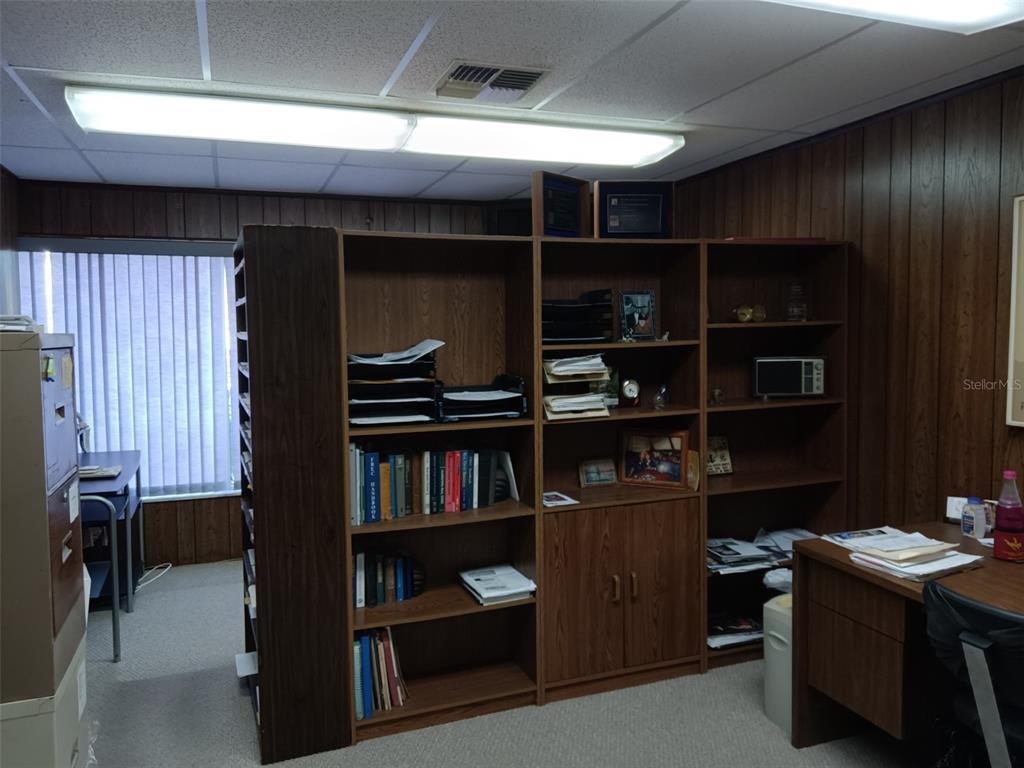 An office space features wood-paneled walls, a large shelving unit, and a desk — 6967 SUNSET DRIVE S, ST PETERSBURG, FL
