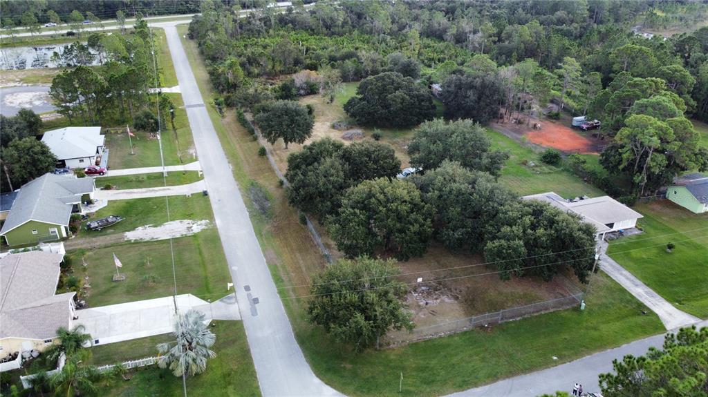 An aerial view shows a vacant, tree-covered residential lot situated between two houses and a road — 101 FLORIDA GRACKLE COURT, FROSTPROOF, FL
