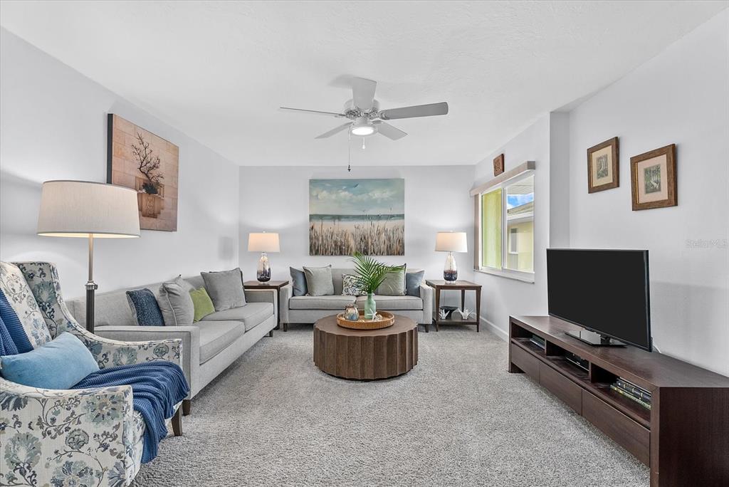 A living room features two gray sofas, a round coffee table, and a television console — 101 LOUELLA LANE UNIT 10, NOKOMIS, FL