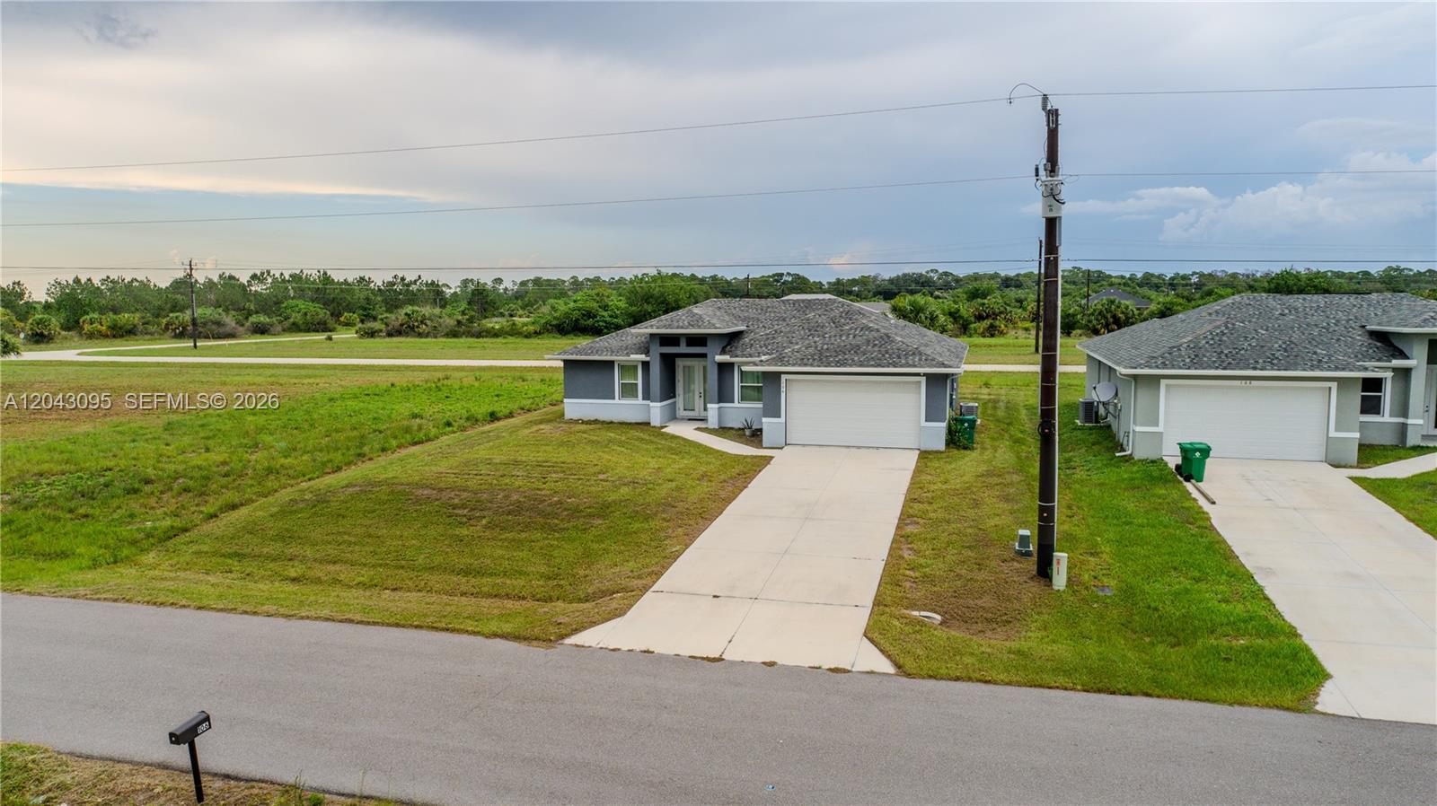 A single-story gray house with a two-car garage sits on a grassy lot — 106 Plantation Dr, La Belle FL 33935, LA BELLE, FL