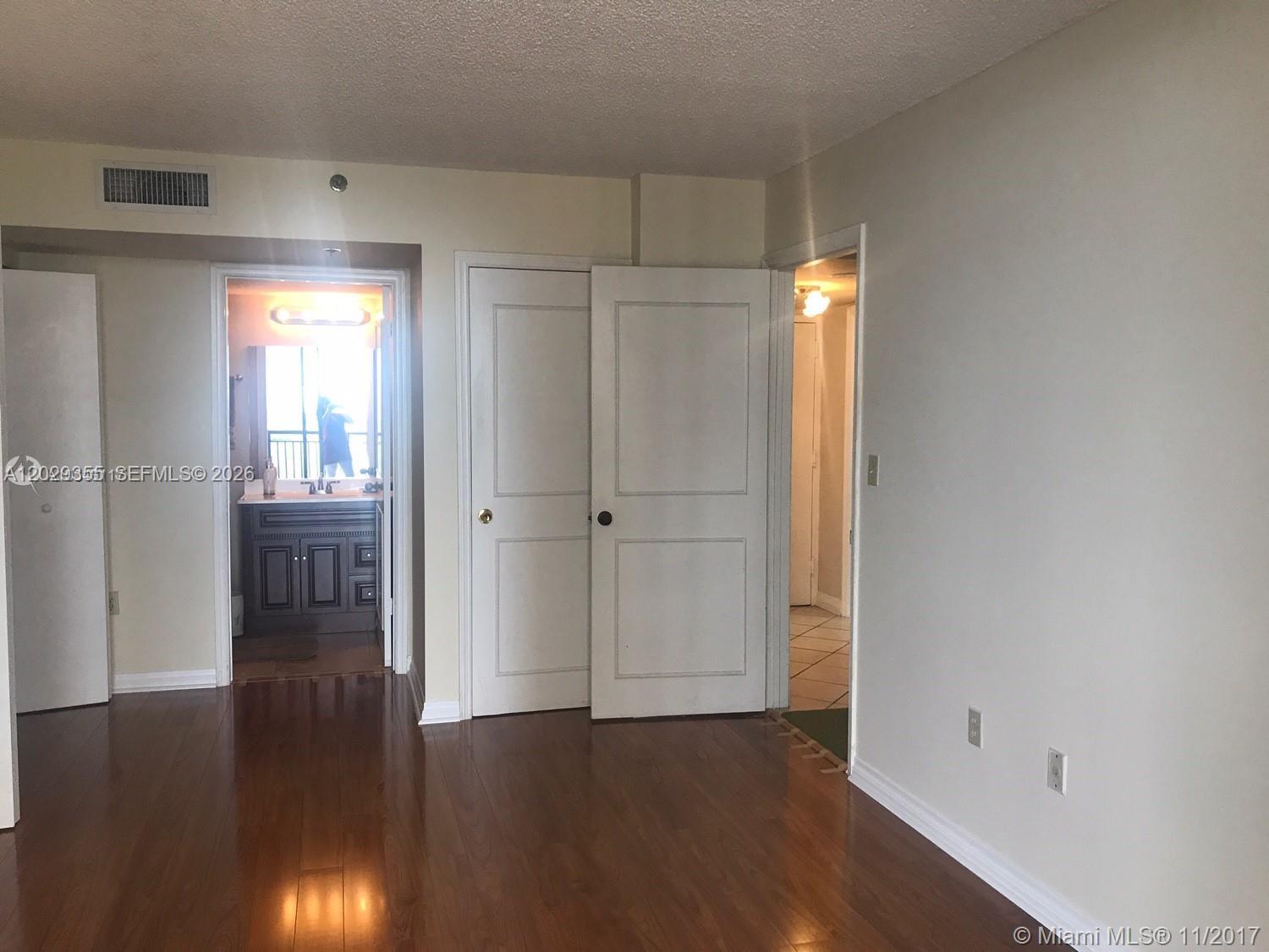 An interior room features hardwood floors, white walls, two closed doors, and an open bathroom — 540 Brickell Key Dr # 1122, Miami FL 33131, MIAMI, FL