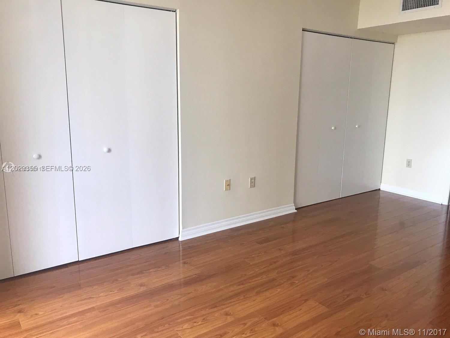 A room with light-colored walls, wood-look flooring, and two sets of white closet doors — 540 Brickell Key Dr # 1122, Miami FL 33131, MIAMI, FL
