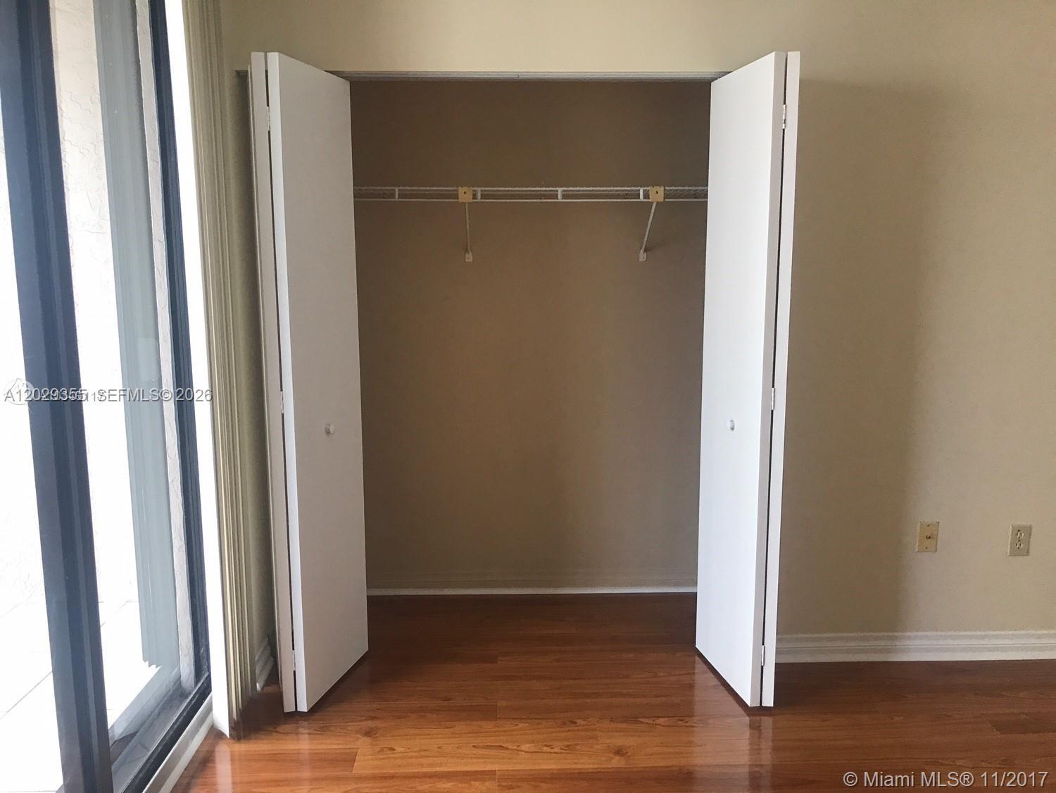 A closet with white bifold doors and a wire shelf sits on a wood floor — 540 Brickell Key Dr # 1122, Miami FL 33131, MIAMI, FL