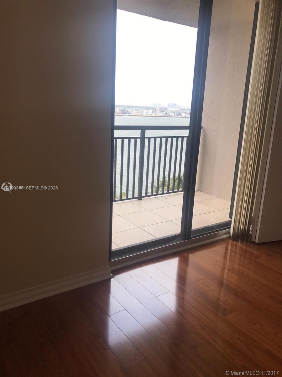 A room with hardwood floors features a sliding glass door leading to a balcony — 540 Brickell Key Dr # 1122, Miami FL 33131, MIAMI, FL