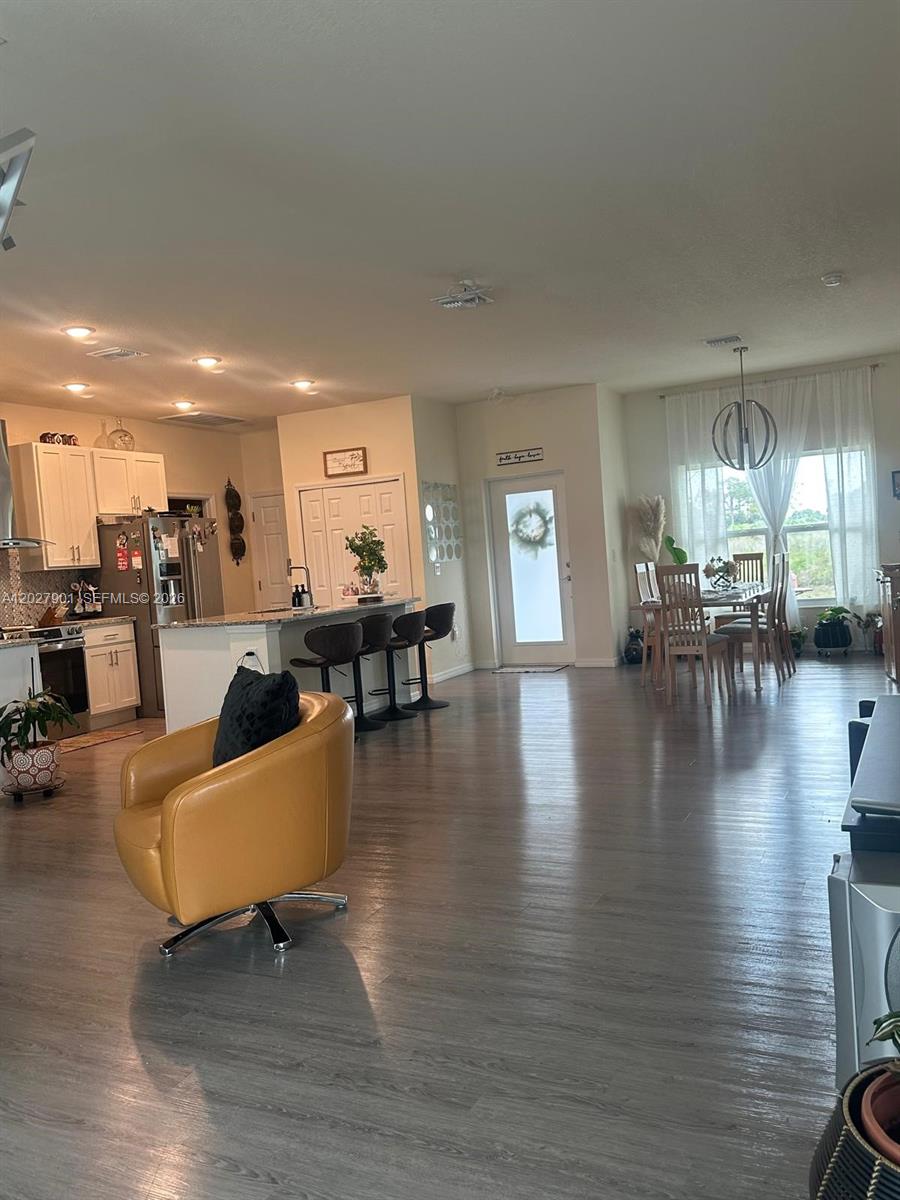 An open-concept kitchen and dining area features white cabinetry, a breakfast bar, and wood-look flooring — 9020 MAC Ct, La Belle FL 33935, LA BELLE, FL