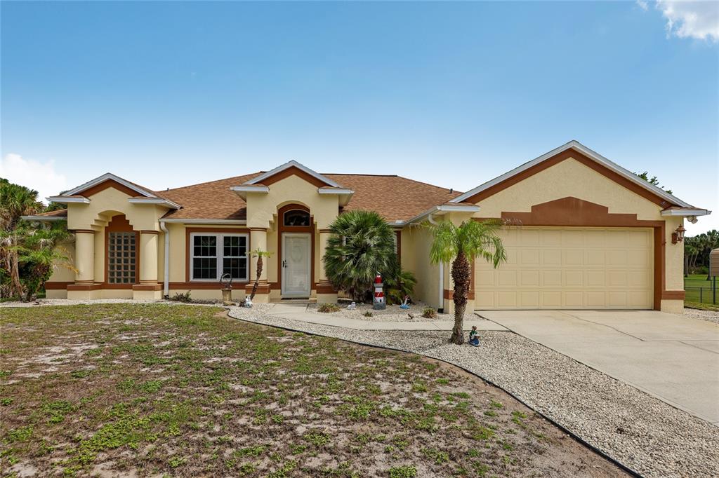A single-story house with a beige stucco exterior, a two-car garage, and a gravel yard — 4880 DATE PALM, COCOA, FL