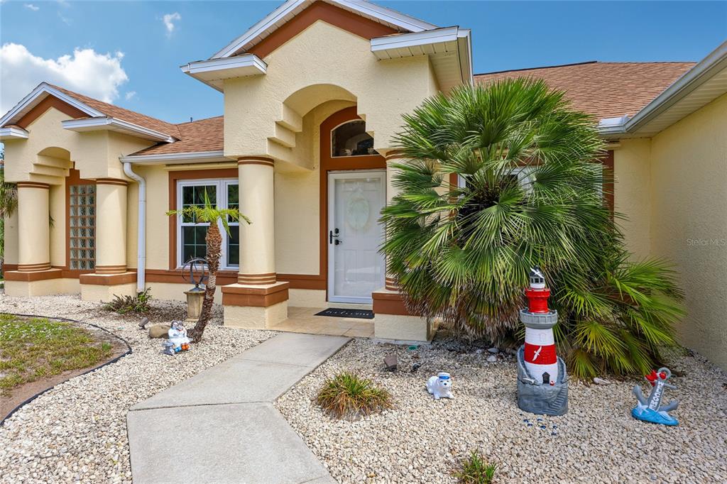 The exterior of a beige house features a front entrance, a palm tree, and decorations — 4880 DATE PALM, COCOA, FL
