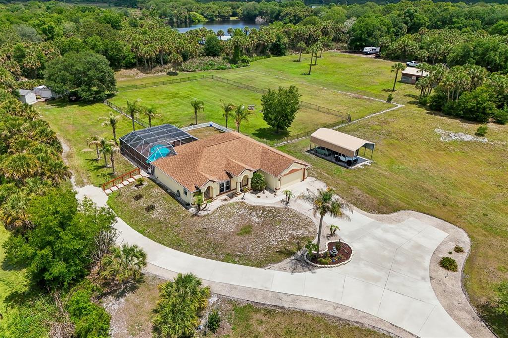 An aerial view shows a house with a pool enclosure, carport, and large fenced yard — 4880 DATE PALM, COCOA, FL