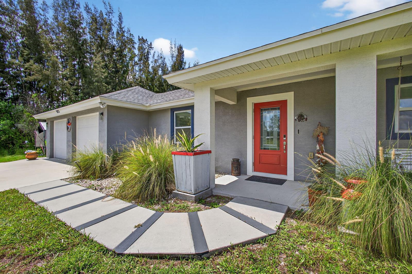 A house exterior features a red front door, a curved concrete walkway, and landscaping — 14171 Biddex Road, FL 33470, FL