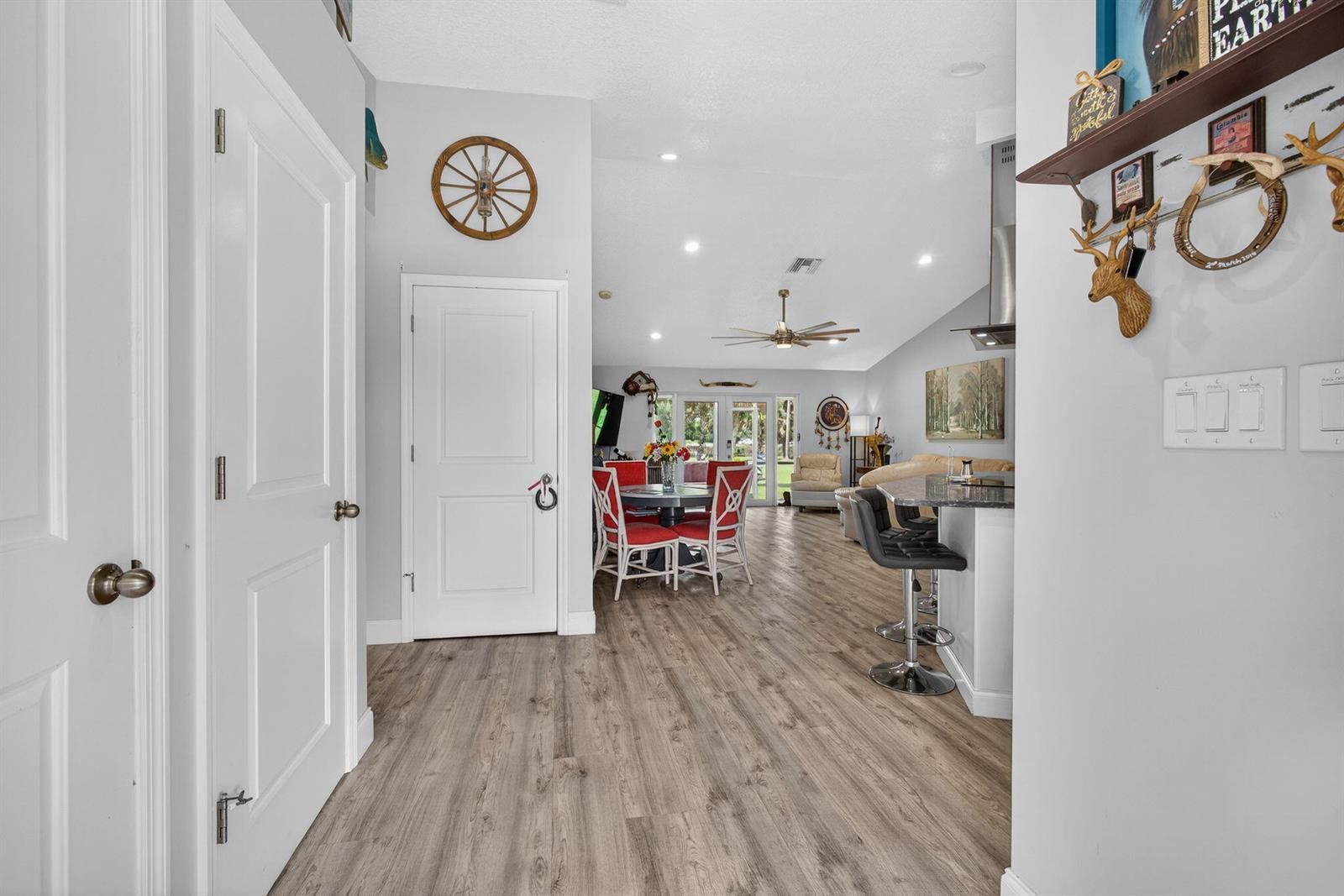 A hallway leads into an open-concept living area with wood-look flooring and a kitchen island — 14171 Biddex Road, FL 33470, FL