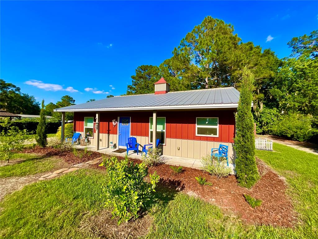A single-story house with red and tan siding, a metal roof, and a blue door — 529 SE 5TH AVENUE, MELROSE, FL