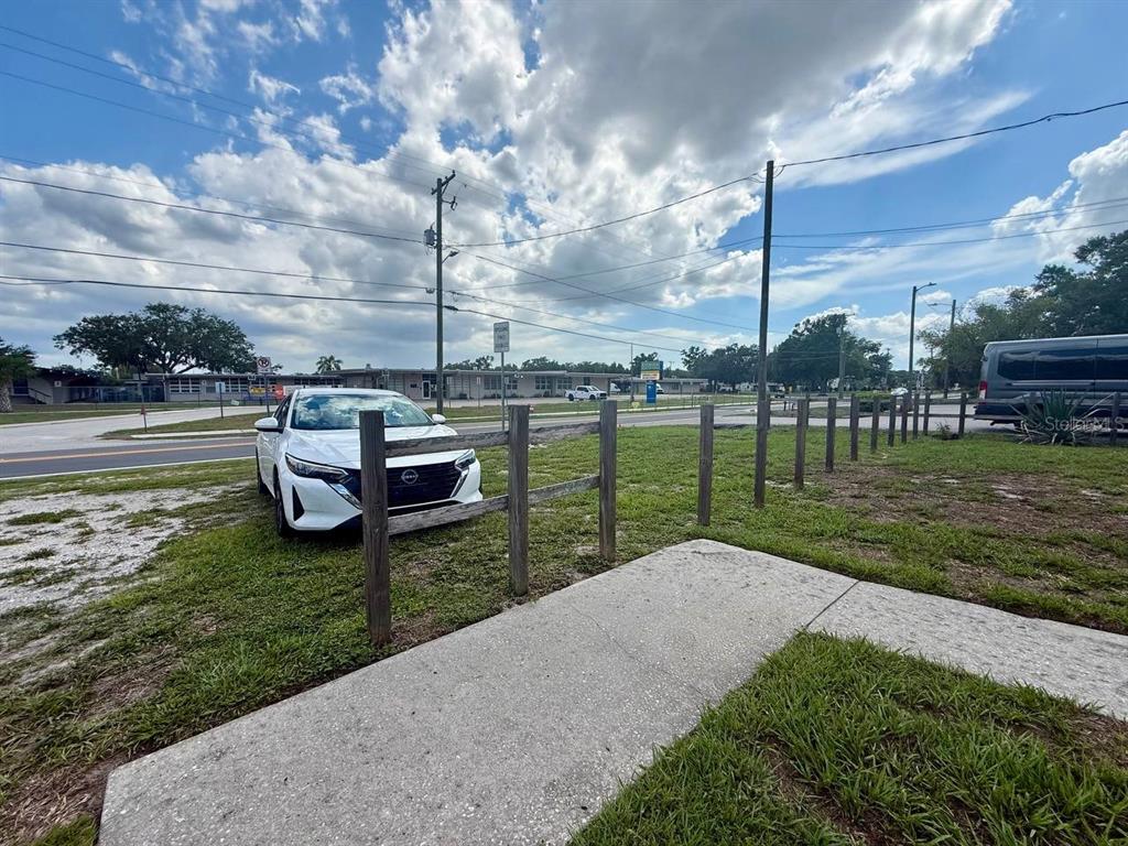 A white car is parked on grass next to a wooden fence and sidewalk — 10812 HANNAWAY DRIVE UNIT C, RIVERVIEW, FL
