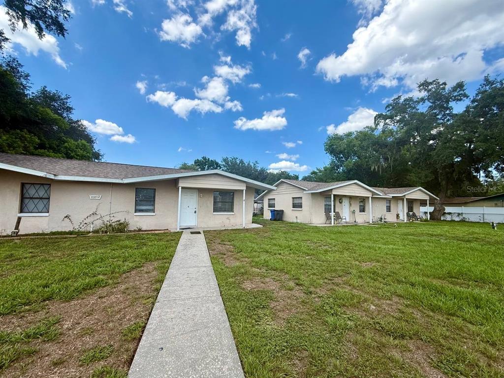 A single-story duplex with a concrete walkway leading to the front doors under a blue sky — 10812 HANNAWAY DRIVE UNIT C, RIVERVIEW, FL