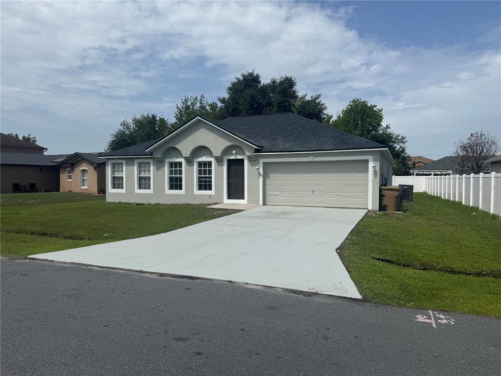 A single-story house with a gray stucco exterior, a dark roof, and a concrete driveway — 760 PALAISEAU COURT, KISSIMMEE, FL