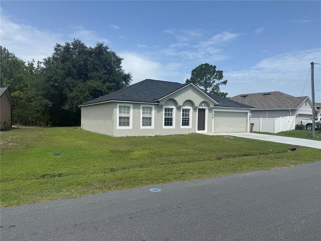 A single-story house with a light-colored stucco exterior, dark roof, and an attached garage — 760 PALAISEAU COURT, KISSIMMEE, FL