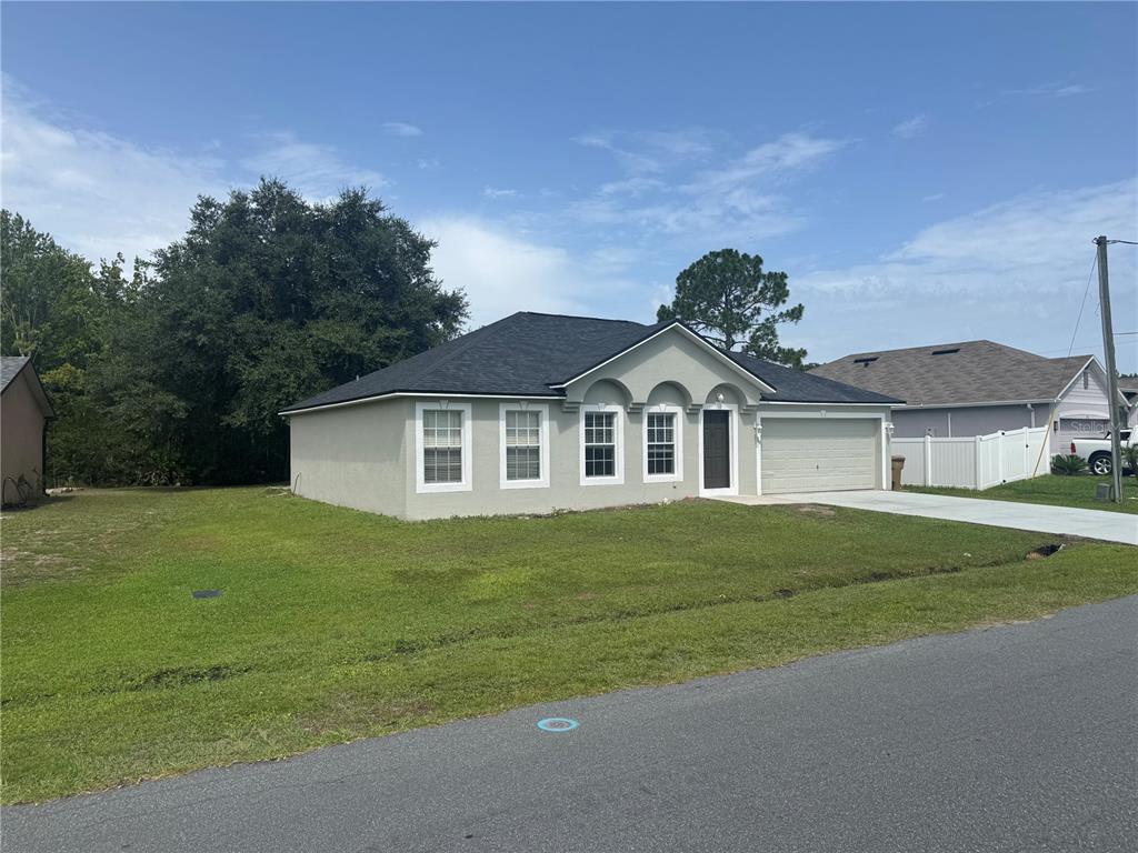 A single-story house with a light-colored stucco exterior, dark roof, and attached garage — 760 PALAISEAU COURT, KISSIMMEE, FL