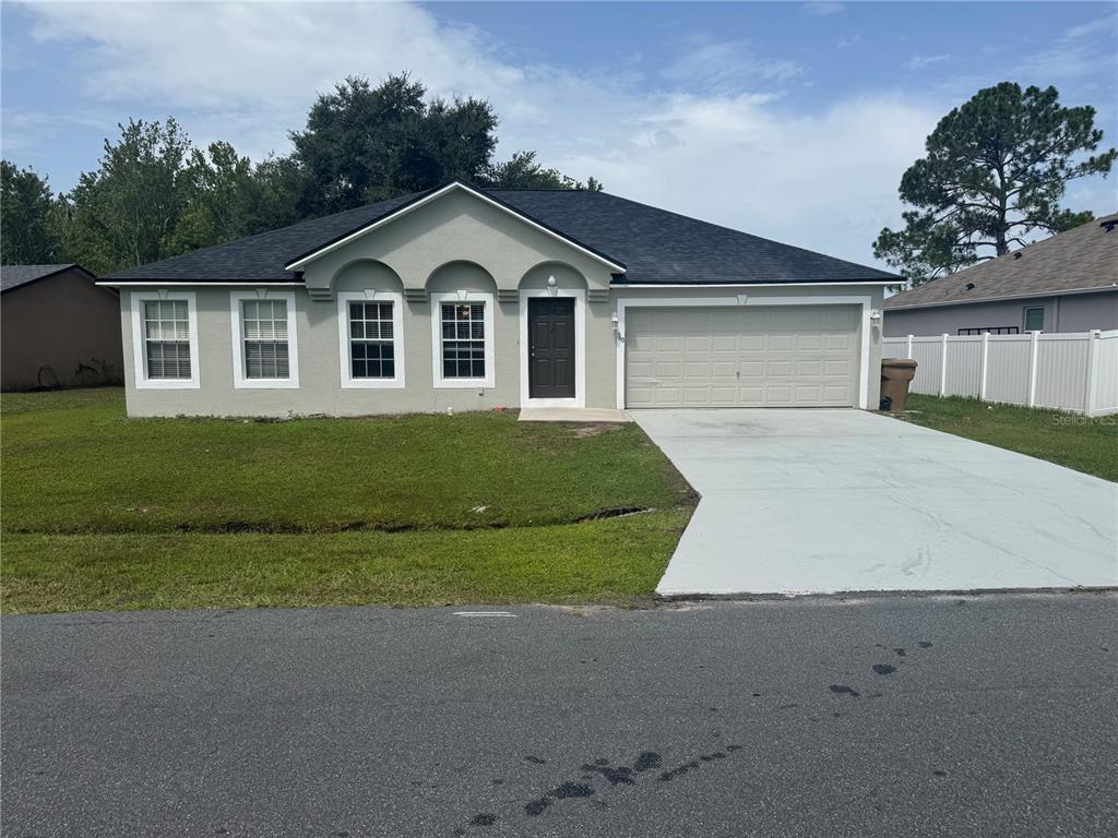 A single-story house with a light-colored stucco exterior, dark roof, and an attached two-car garage — 760 PALAISEAU COURT, KISSIMMEE, FL