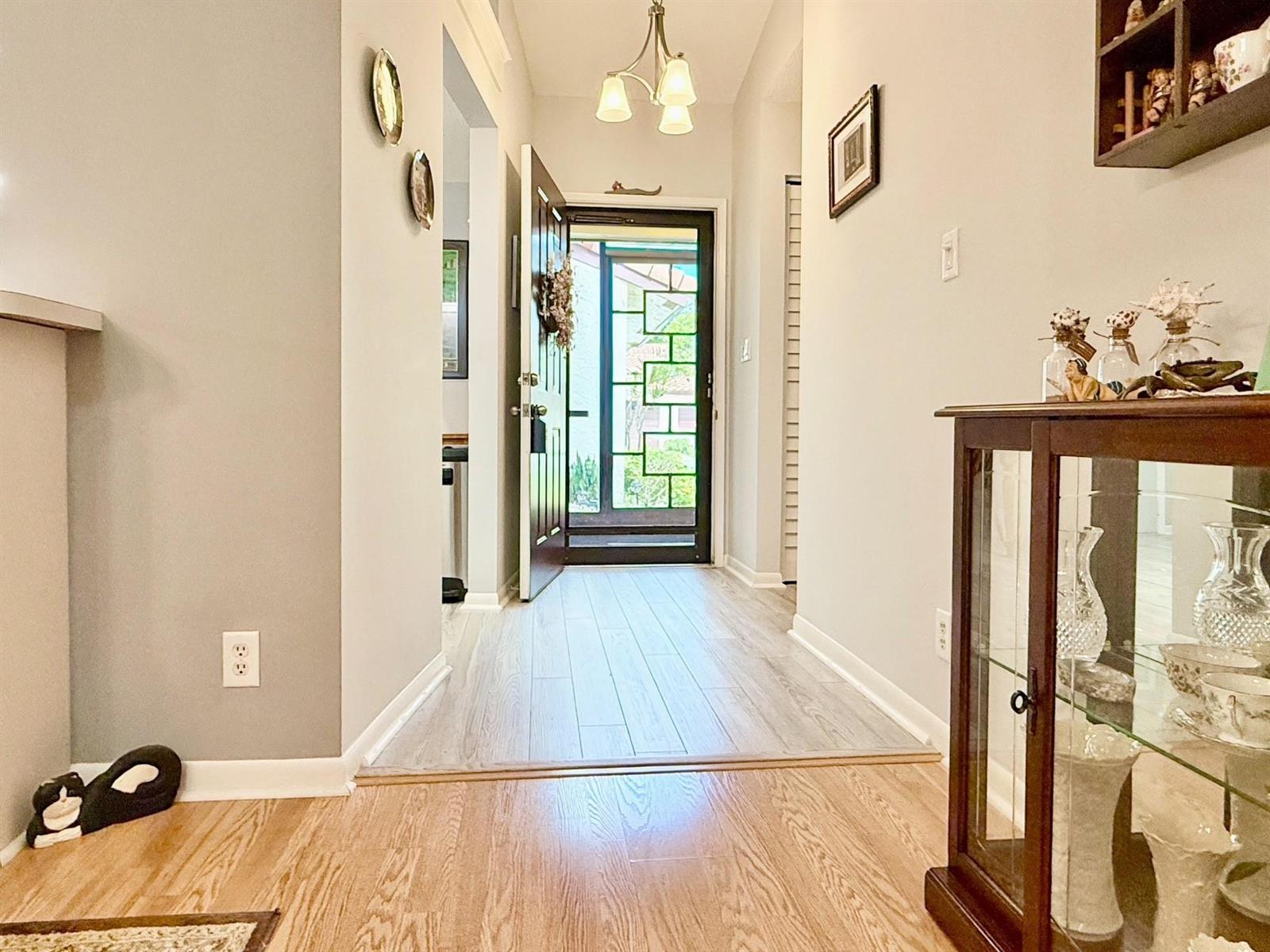 A foyer with light wood flooring, a glass-paneled front door, and a wooden display cabinet — 5462 Palm Springs Lane # A, Boynton Beach FL 33437, BOYNTON BEACH, FL