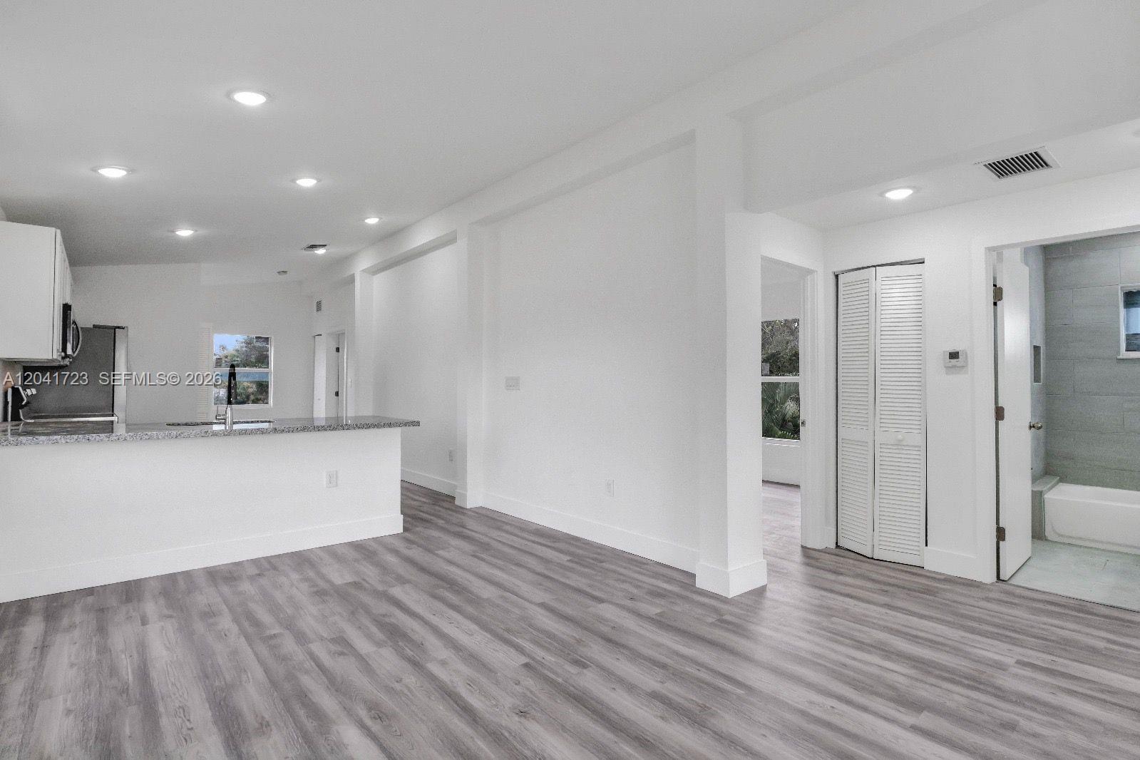 A kitchen with a breakfast bar opens into a living area with wood-look flooring — 7777 NW 8th Ct # A, Miami FL 33150, MIAMI, FL