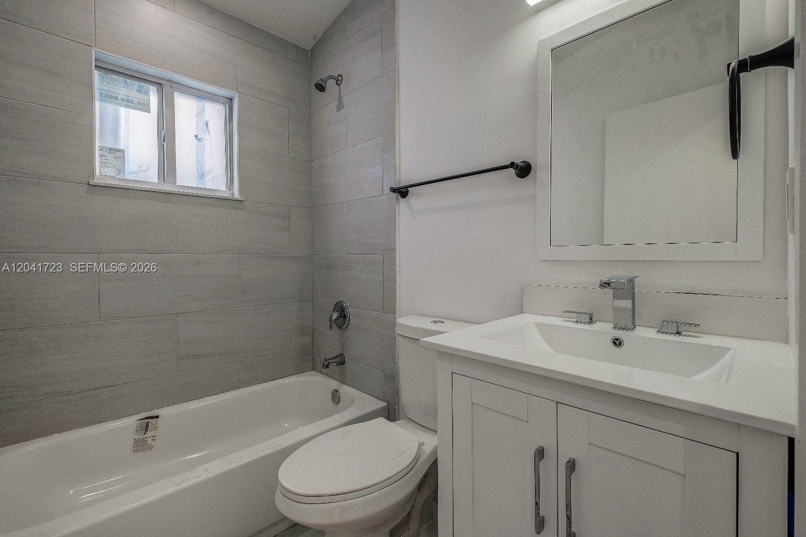 A bathroom features a white vanity, a toilet, and a bathtub with gray tiled walls — 7777 NW 8th Ct # A, Miami FL 33150, MIAMI, FL
