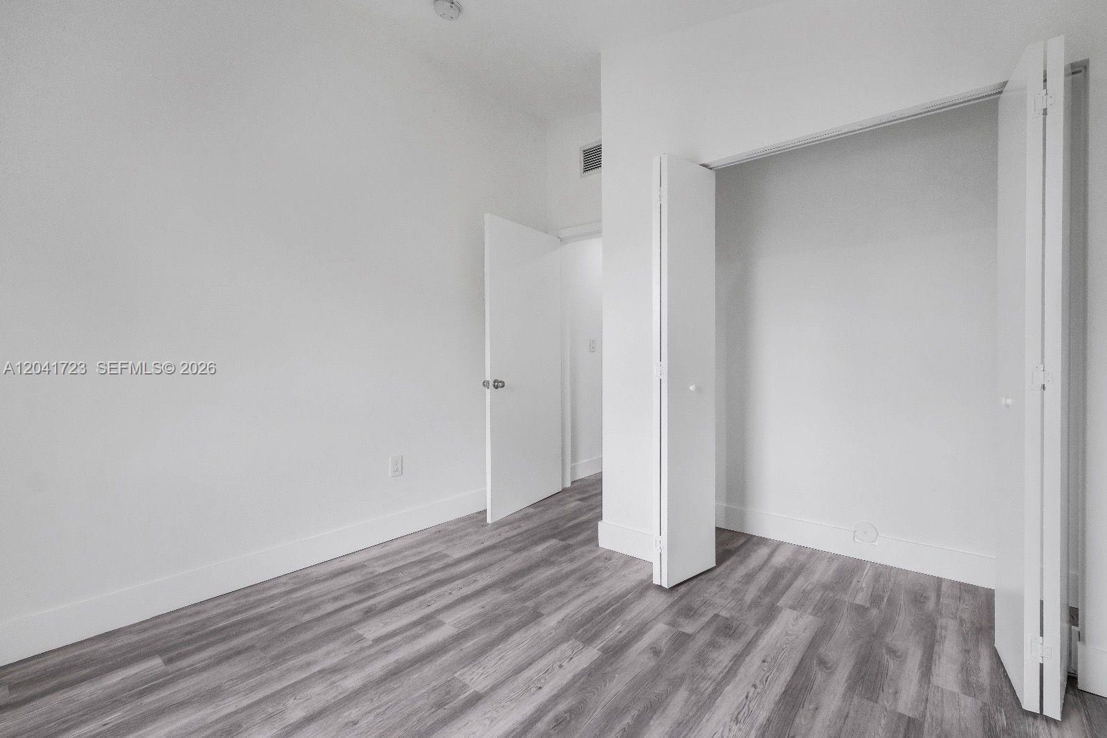 An empty room features white walls, gray wood-look flooring, and an open closet — 7777 NW 8th Ct # A, Miami FL 33150, MIAMI, FL