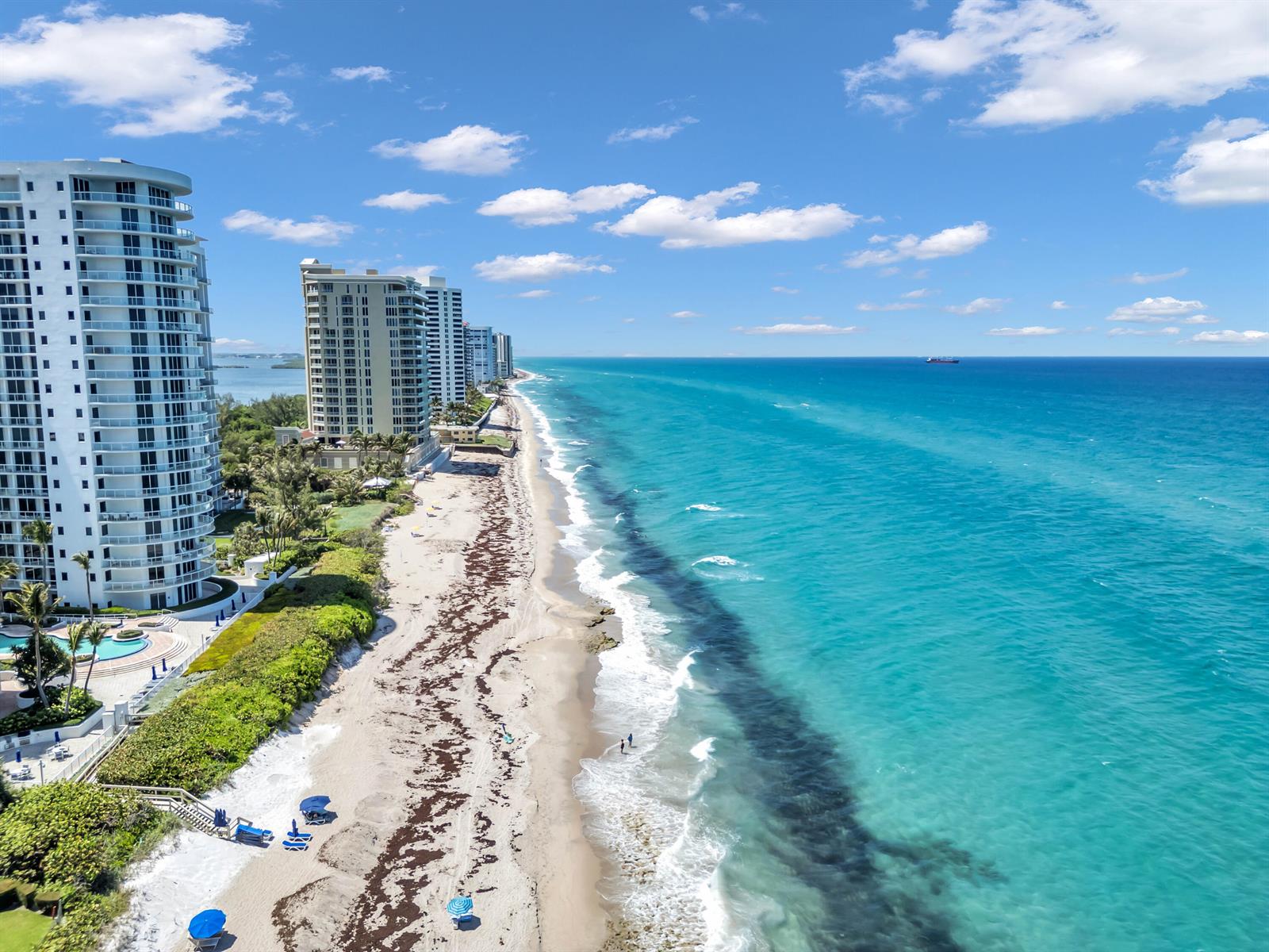 An aerial view shows high-rise condominiums along a sandy beach with turquoise ocean water — 4100 N Ocean Drive # 1101, West Palm Beach FL 33404, WEST PALM BEACH, FL