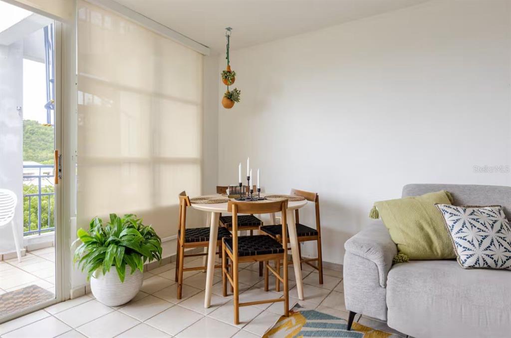A dining area with a round table and chairs sits next to a living room sofa — COLONIA SANTA MARIA COSTA BRAVA CONDOMINIUM UNIT 8-401, CEIBA, PR
