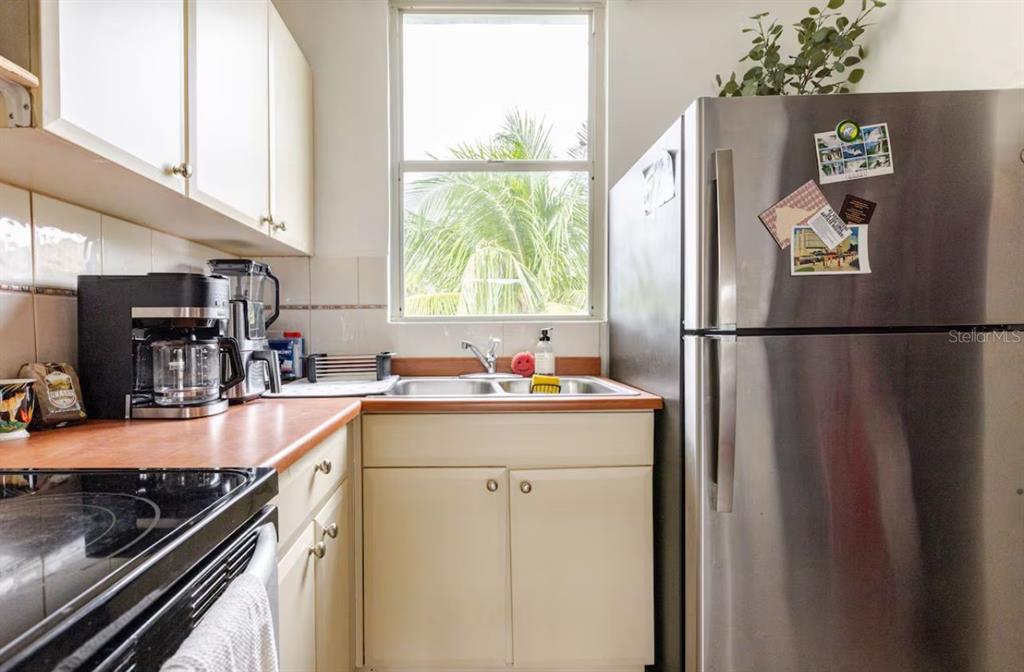 A kitchen features a stainless steel refrigerator, a sink, and light-colored cabinets — COLONIA SANTA MARIA COSTA BRAVA CONDOMINIUM UNIT 8-401, CEIBA, PR