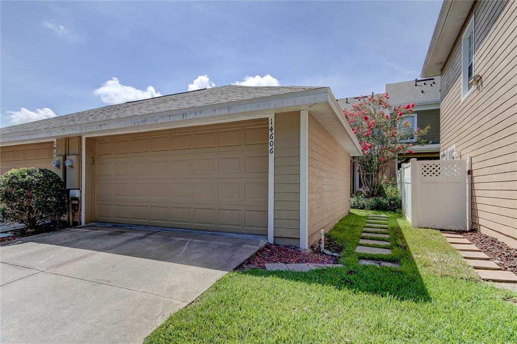 A brick exterior home features a covered porch, a white front door, and green landscaping — 14606 BOURNEMOUTH ROAD, TAMPA, FL