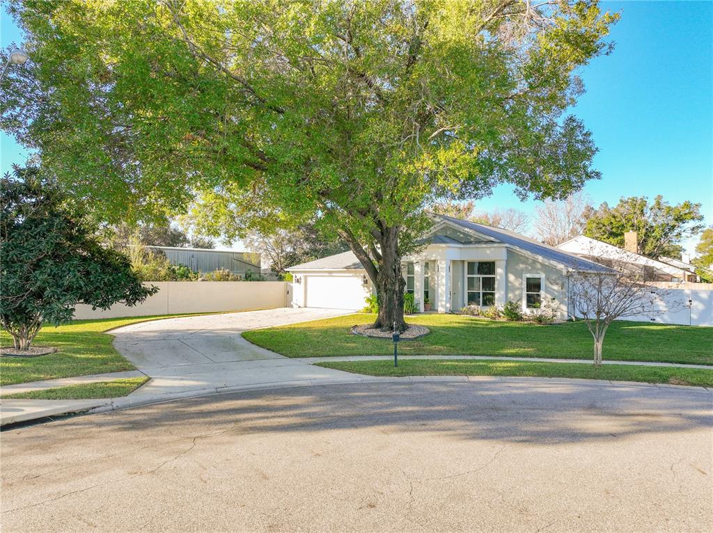 A single-story house with a large tree in the front yard and a concrete driveway — 9244 BEAVER COVE, APOPKA, FL