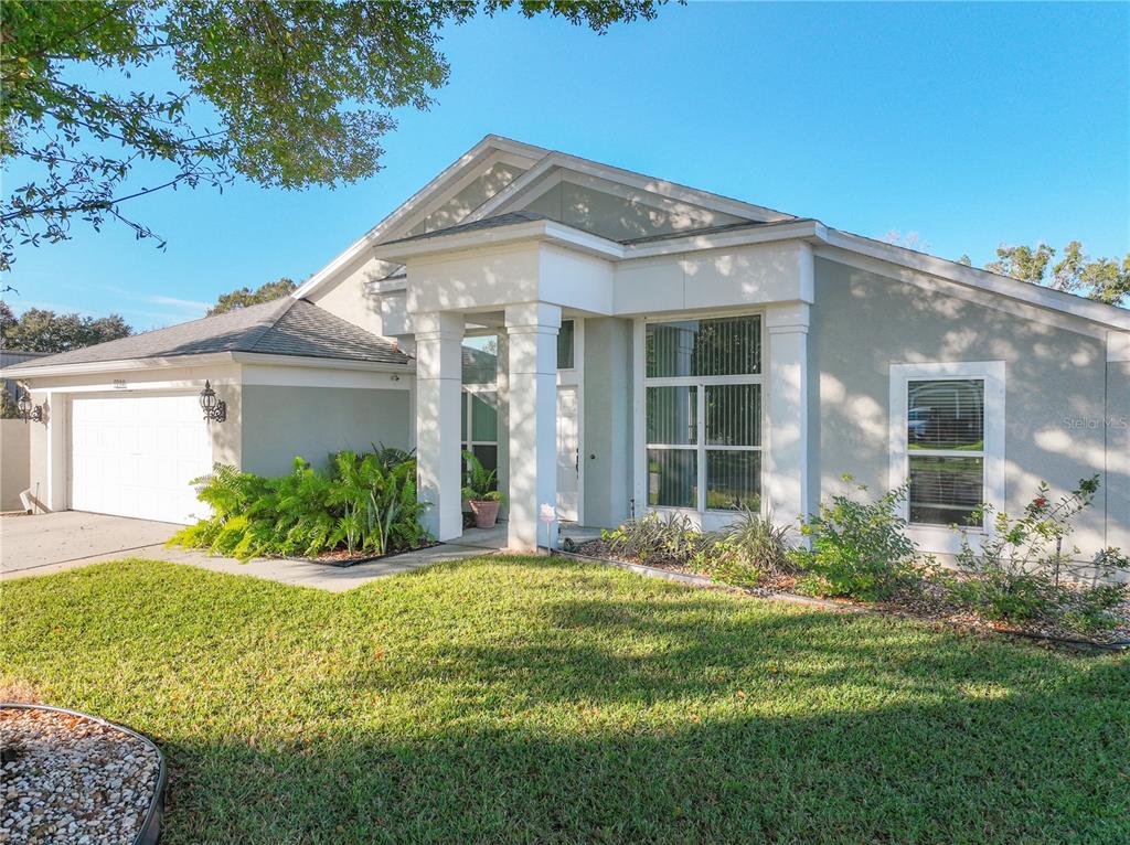 A single-story house with a white garage, a covered entryway, and a green lawn — 9244 BEAVER COVE, APOPKA, FL