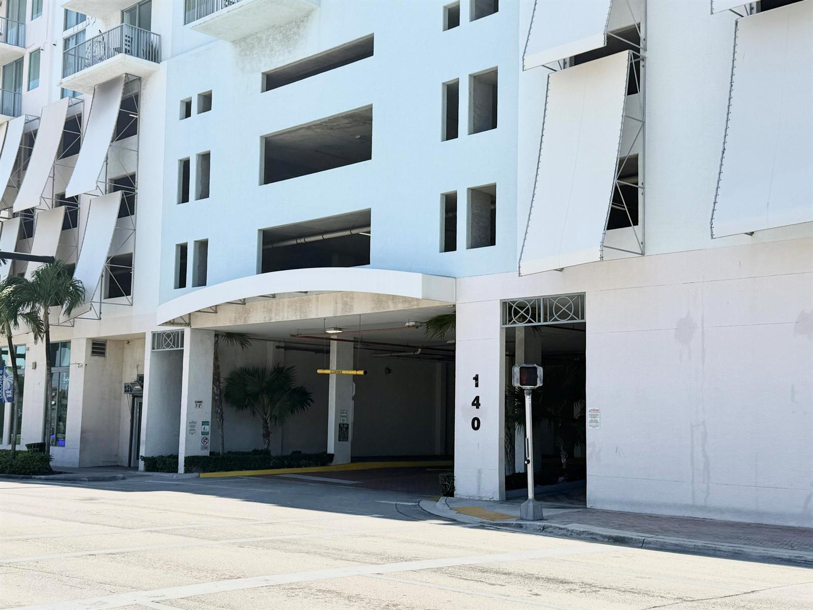The exterior of a white multi-story building features a covered parking garage entrance — 140 S Dixie Highway # 512, Hollywood FL 33020, HOLLYWOOD, FL