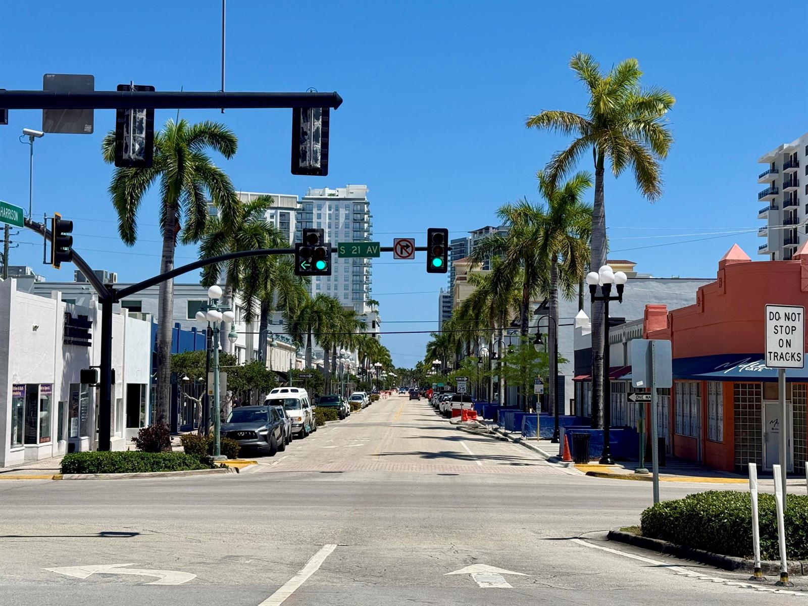 An urban street intersection with palm trees, traffic lights, and buildings under a clear sky — 140 S Dixie Highway # 512, Hollywood FL 33020, HOLLYWOOD, FL