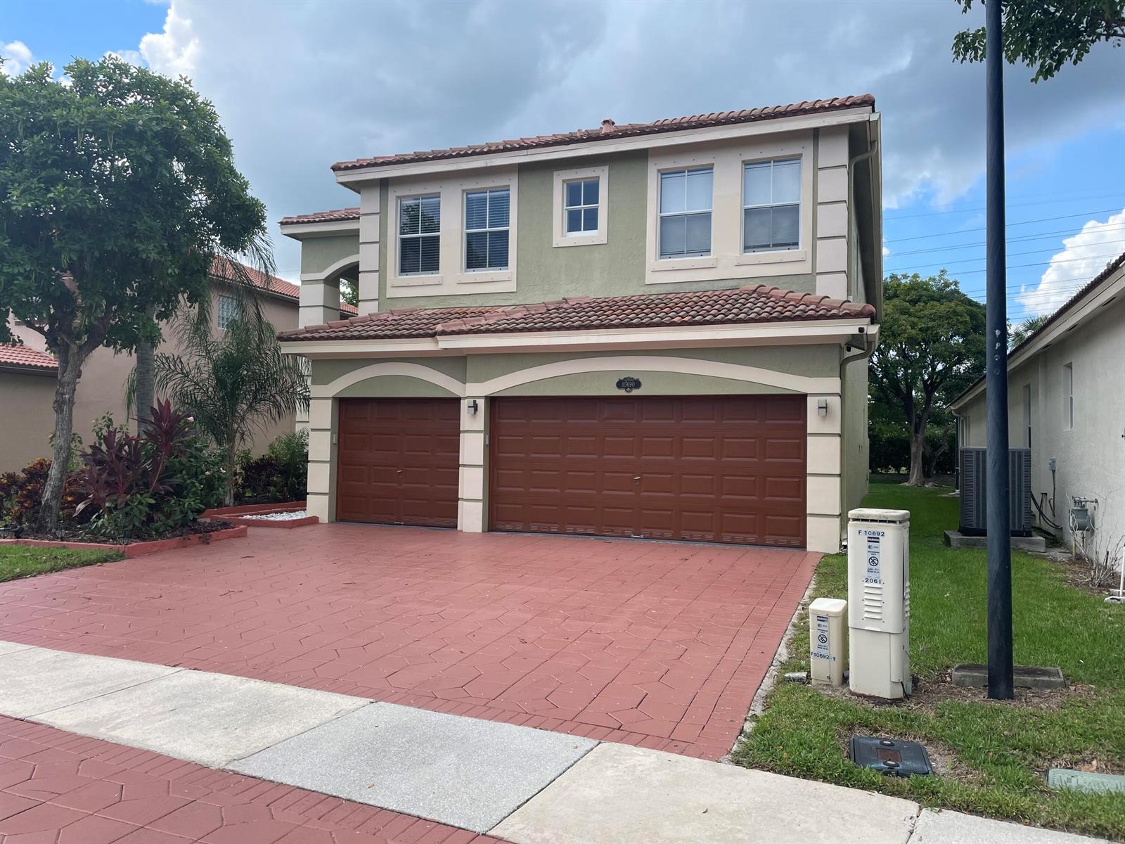 A two-story house with a red-tiled roof, green stucco exterior, and a three-car garage — 10690 Old Hammock Way, Wellington FL 33414, WELLINGTON, FL