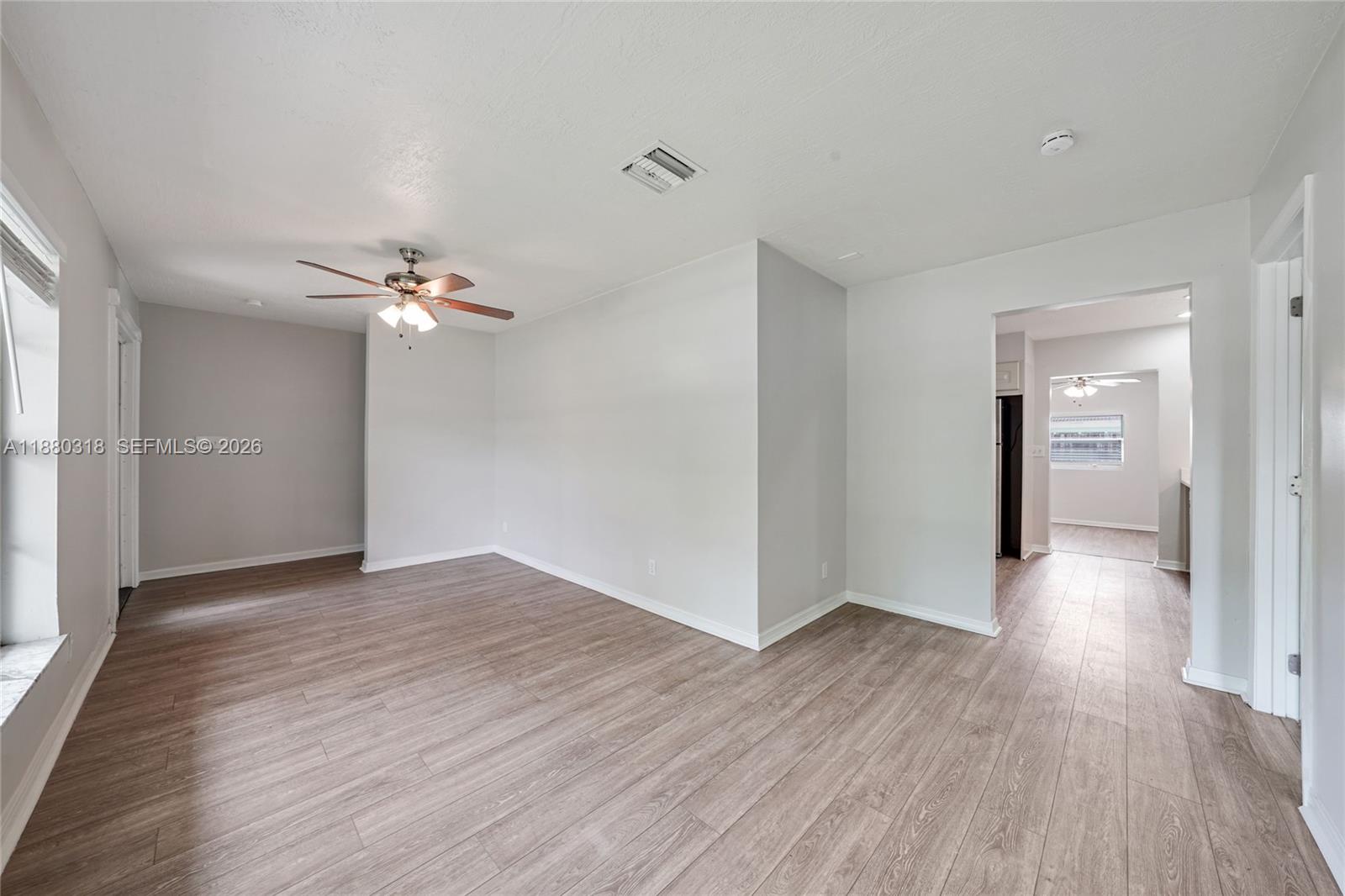 An empty room features light wood-look flooring, white walls, and a ceiling fan — 1000 NW 17th Ave, Boca Raton FL 33486, BOCA RATON, FL