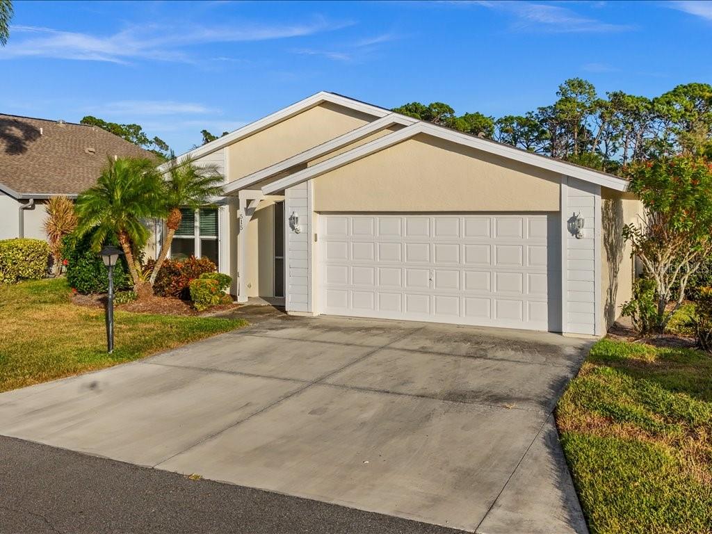 A single-story house with a beige stucco exterior, white garage door, and a concrete driveway — 515 WEKIVA RIVER COURT UNIT 81, ENGLEWOOD, FL