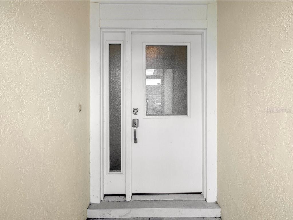 A white front door with a vertical sidelight and a rectangular glass window insert — 515 WEKIVA RIVER COURT UNIT 81, ENGLEWOOD, FL