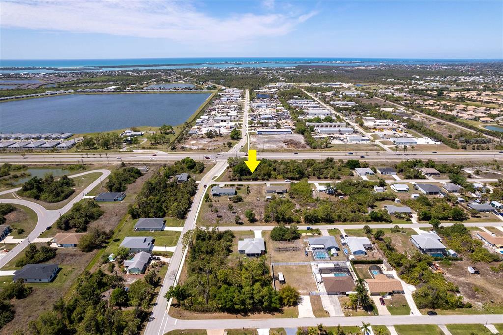 An aerial view shows a vacant lot marked by a yellow arrow in a neighborhood — 7679 CASTLEBERRY TERRACE, ENGLEWOOD, FL