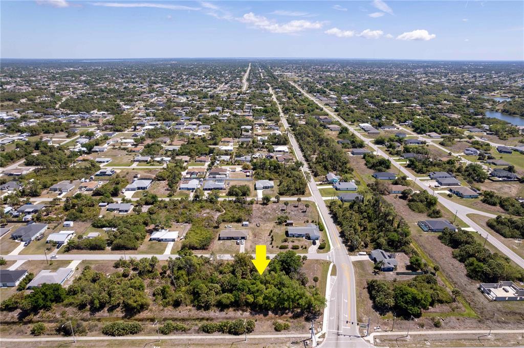 An aerial view shows a vacant, tree-covered lot situated next to a paved road — 7679 CASTLEBERRY TERRACE, ENGLEWOOD, FL