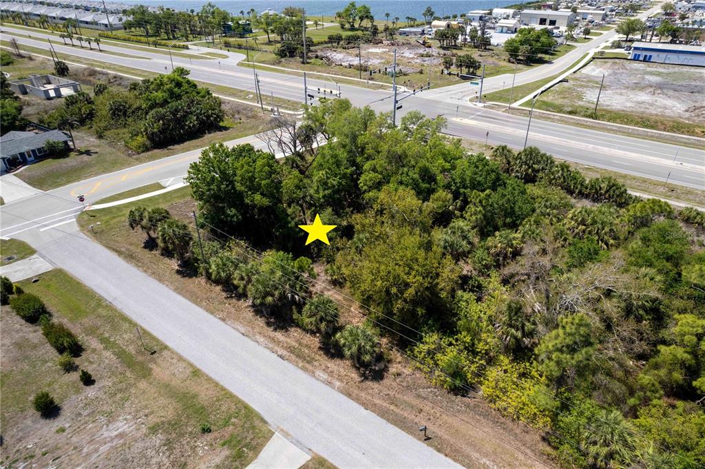 An aerial view shows a vacant, tree-covered lot situated near a road intersection — 7679 CASTLEBERRY TERRACE, ENGLEWOOD, FL