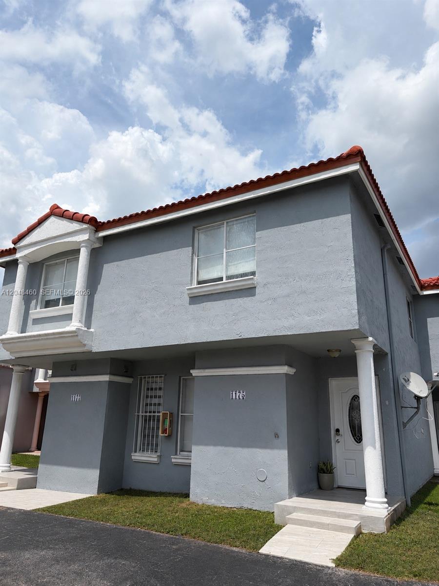 A two-story gray stucco townhouse features a red tile roof and a white front door — 1175 NW 123rd Pl # 210, Miami FL 33182, MIAMI, FL