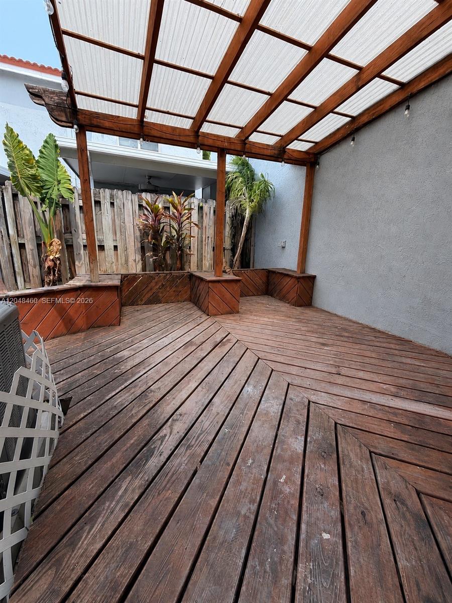 A wooden deck features a pergola, built-in bench seating, and a privacy fence — 1175 NW 123rd Pl # 210, Miami FL 33182, MIAMI, FL