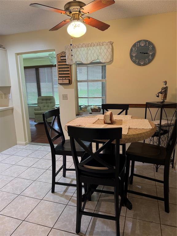 A dining area features a round table with four black chairs and a ceiling fan — 8591 SW 93RD PLACE UNIT B, OCALA, FL