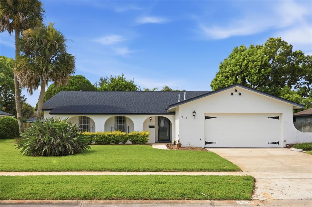 A white house exterior features a covered arched walkway, a front door, and a garage — 2703 TIERRA CIRCLE, WINTER PARK, FL