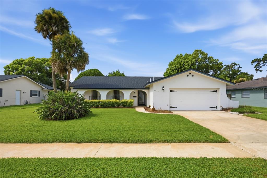 A covered entryway features a white stucco wall, a dark storm door, and a wall-mounted lamp — 2703 TIERRA CIRCLE, WINTER PARK, FL