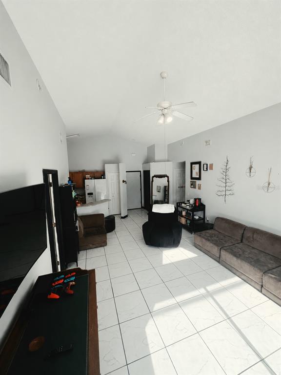 A living room with white tile floors, a vaulted ceiling, and a brown sectional sofa — 324 CASTERTON CIRCLE, DAVENPORT, FL