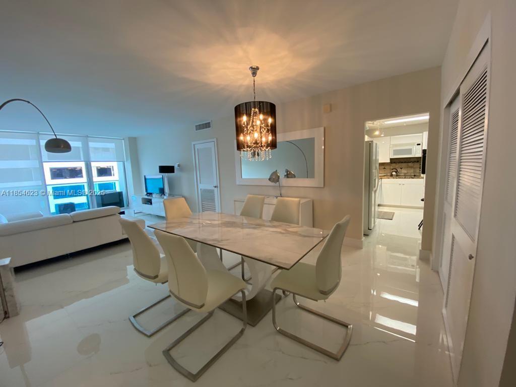 A dining area features a marble table, modern chairs, and a crystal chandelier on tile floors — 4001 S Ocean Dr # 10F, Hollywood FL 33019, HOLLYWOOD, FL