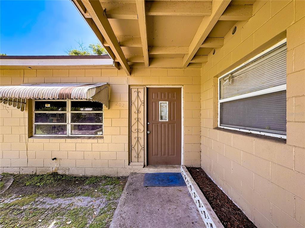 The exterior of a house features a brown front door, a window with an awning, and concrete block walls — 202 N 39TH STREET, FORT PIERCE, FL