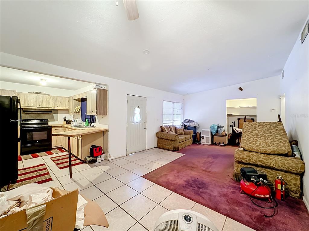 A living room with tile and purple carpet flooring connects to a kitchen area — 202 N 39TH STREET, FORT PIERCE, FL